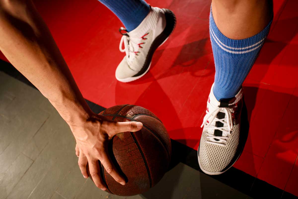 Basketball player holding basketball with one hand.