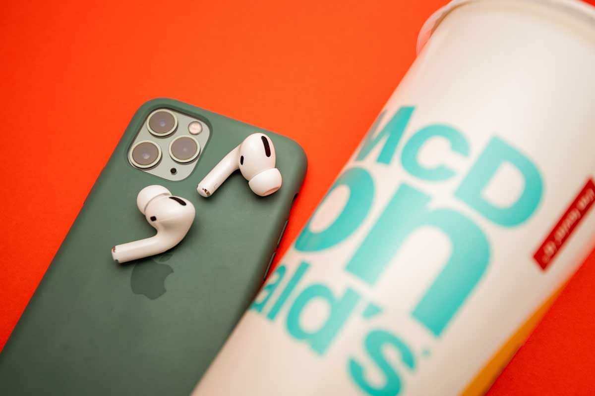 New Apple Computers AirPods Pro headphones with Active Noise Cancellation for immersive sound next to iPhone 11 Pro and McDonalds cup