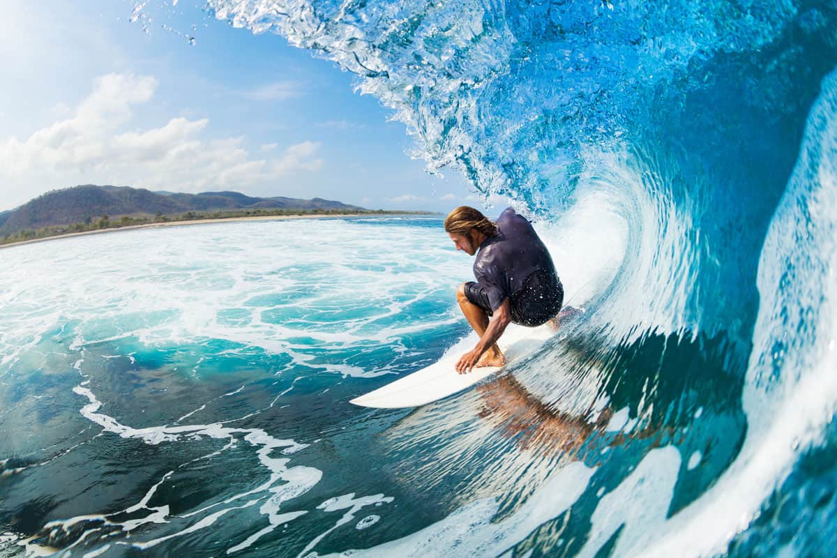 A surfer on blue ocean wave in the tube getting barreled