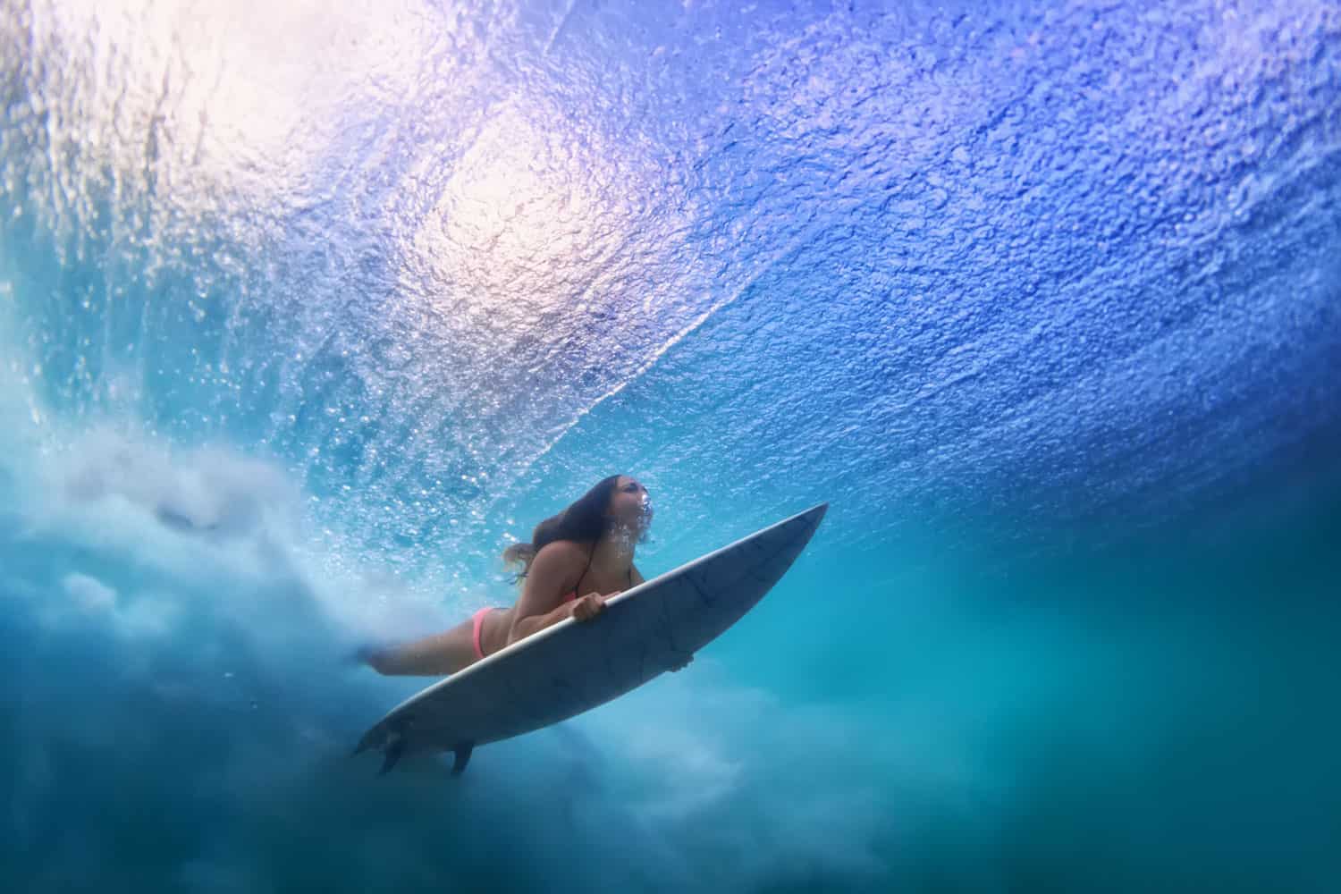 Surfer with surf board dive underwater under breaking ocean wave