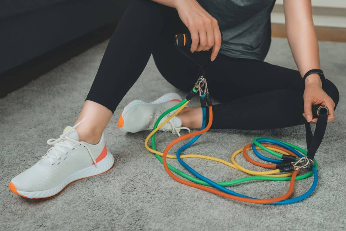 A woman taking a break from using resistance bands on her workout, 5 Types Of Resistance Bands To Know