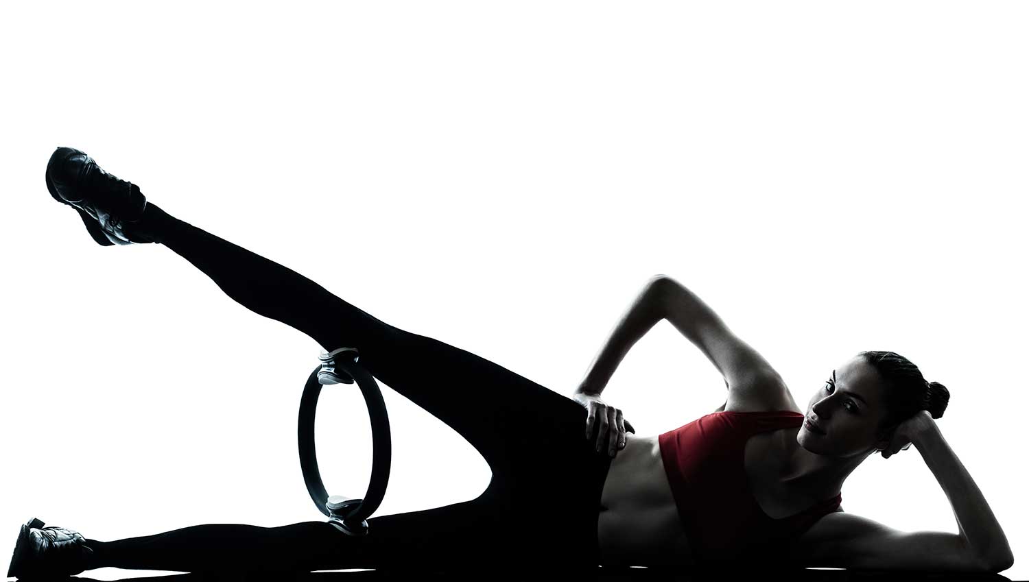 Woman exercising pilates ring in silhouette