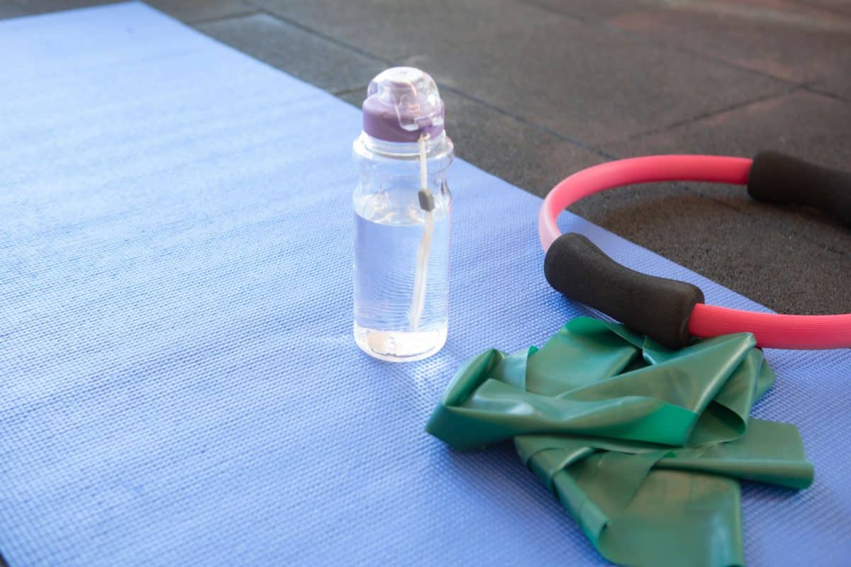 A bottle of water and a pilates ring on the side of the mat
