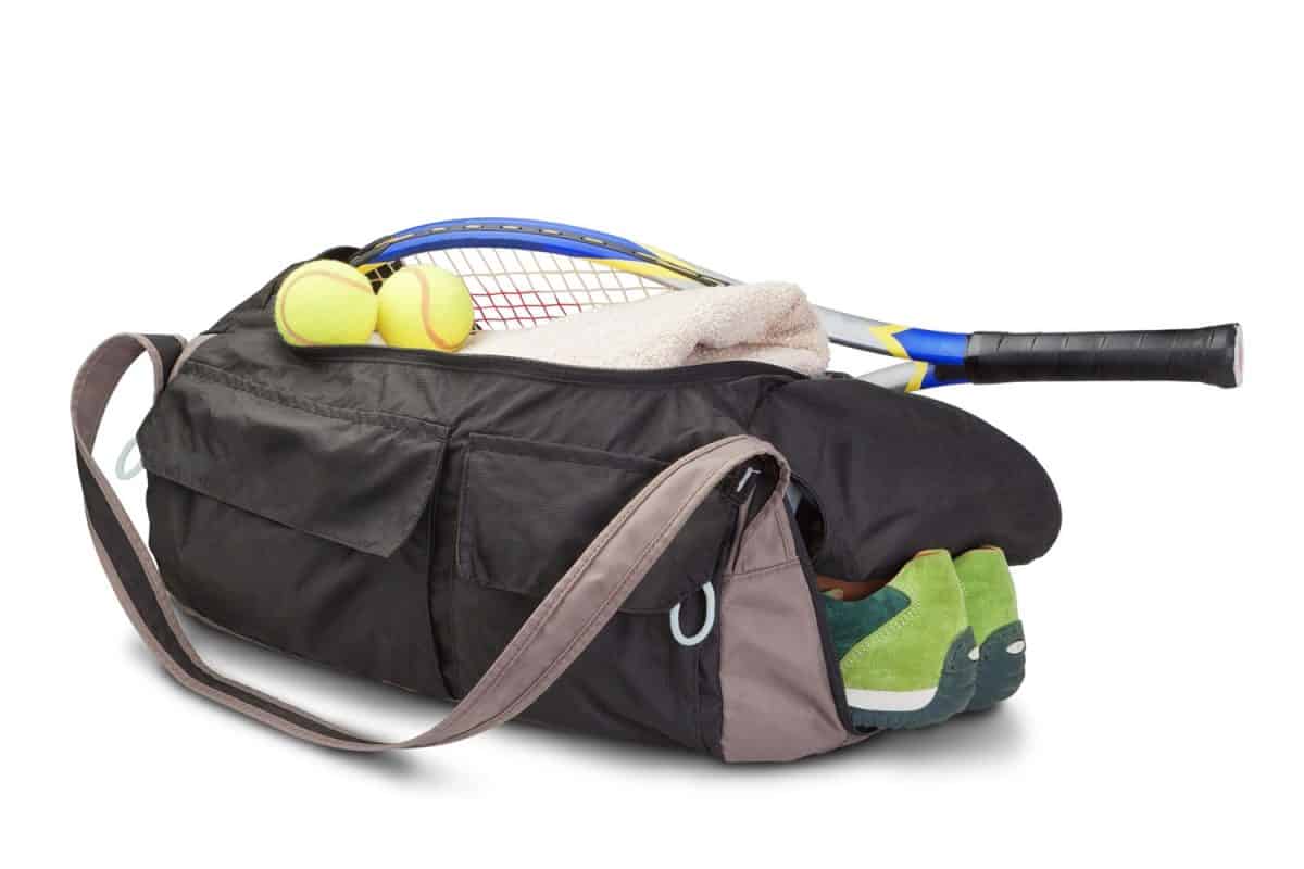 A tennis players bag with a tennis racket tennis and tennis shoes on a white background