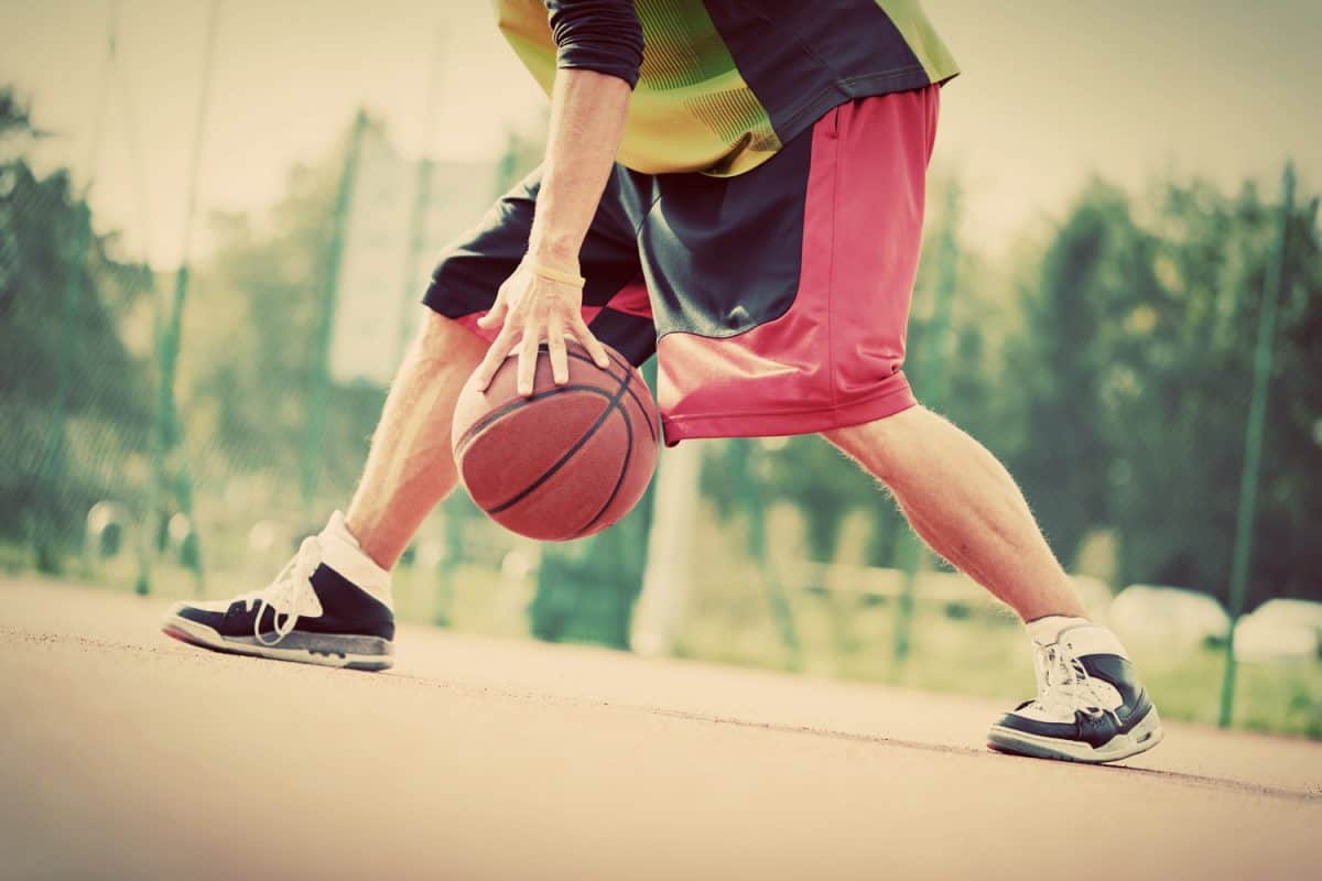 Man on basketball court dribbling with ball.
