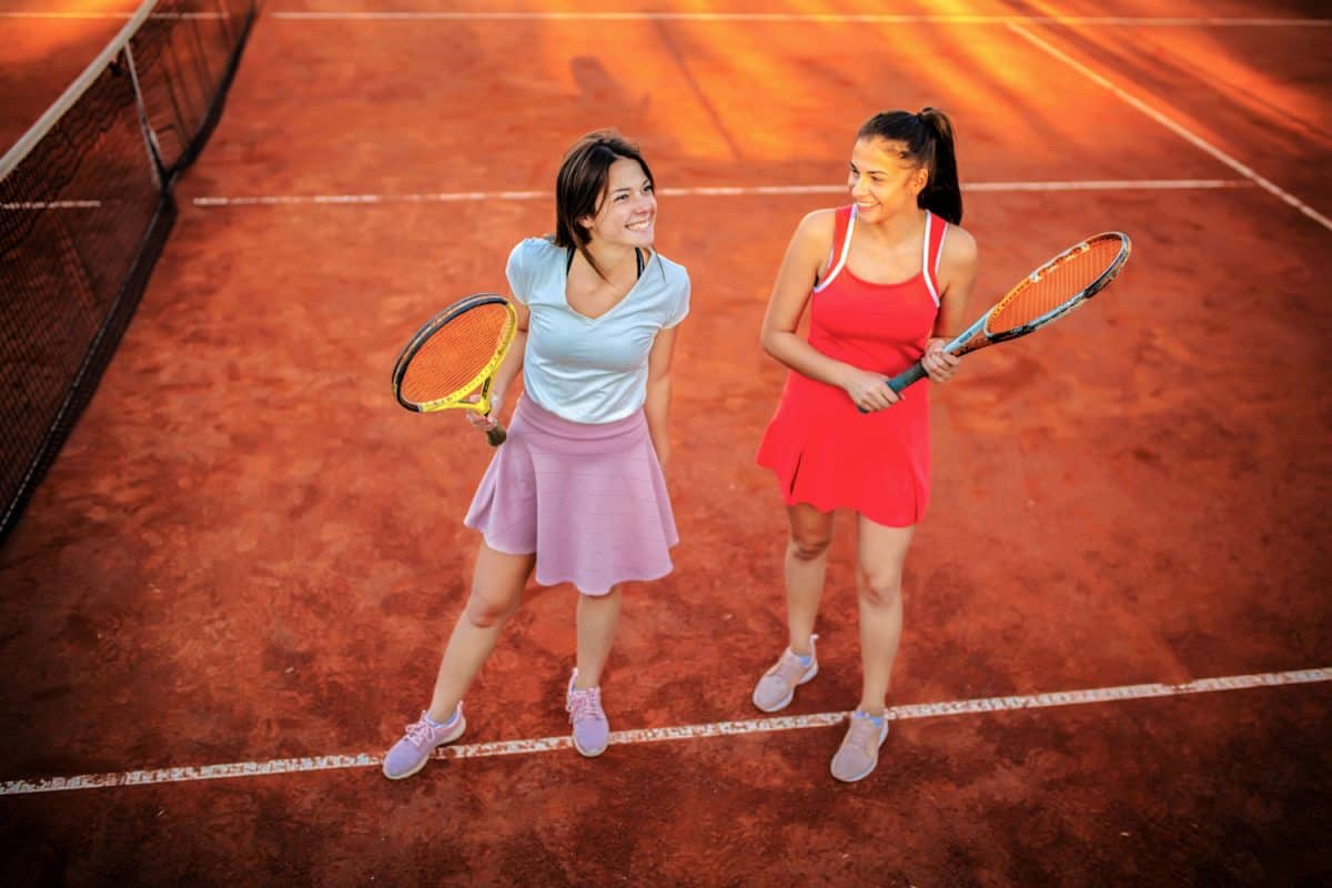 Two attractive tennis players holding tennis rackets