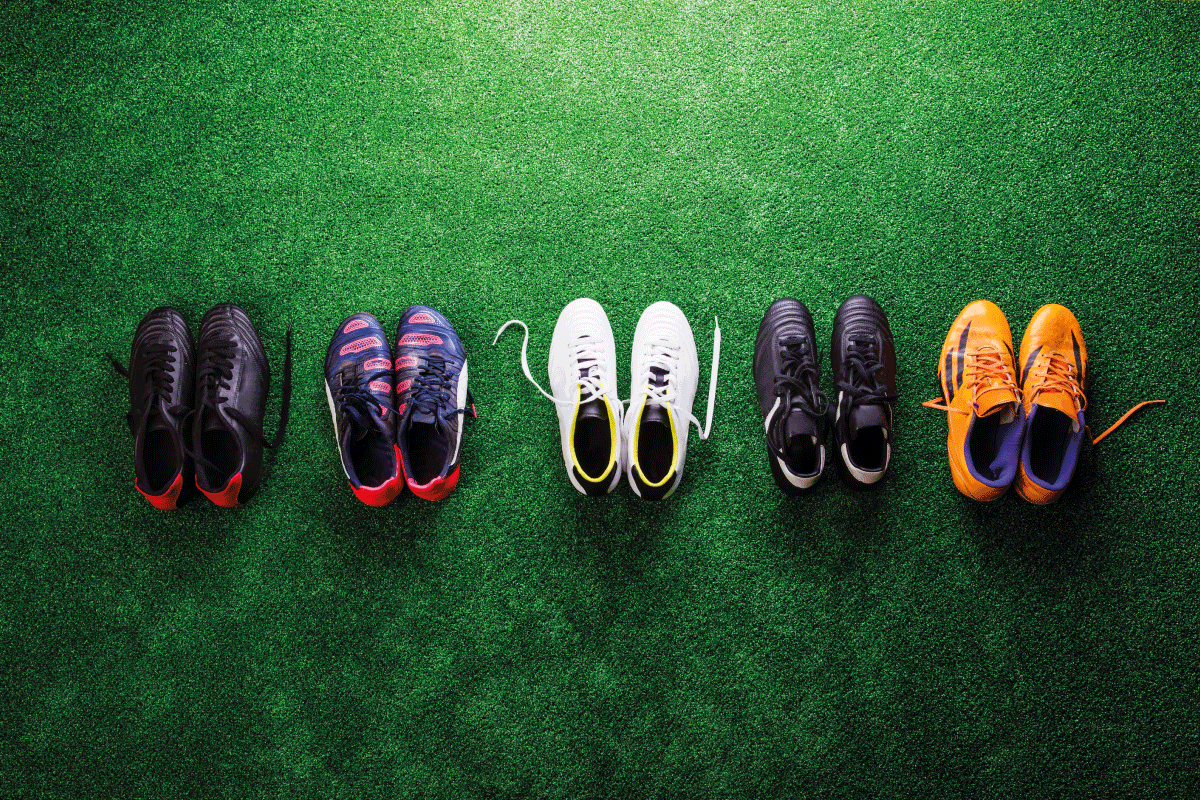 Various colorful cleats against artificial turf. Football Vs Lacrosse Cleats—The Key Differences