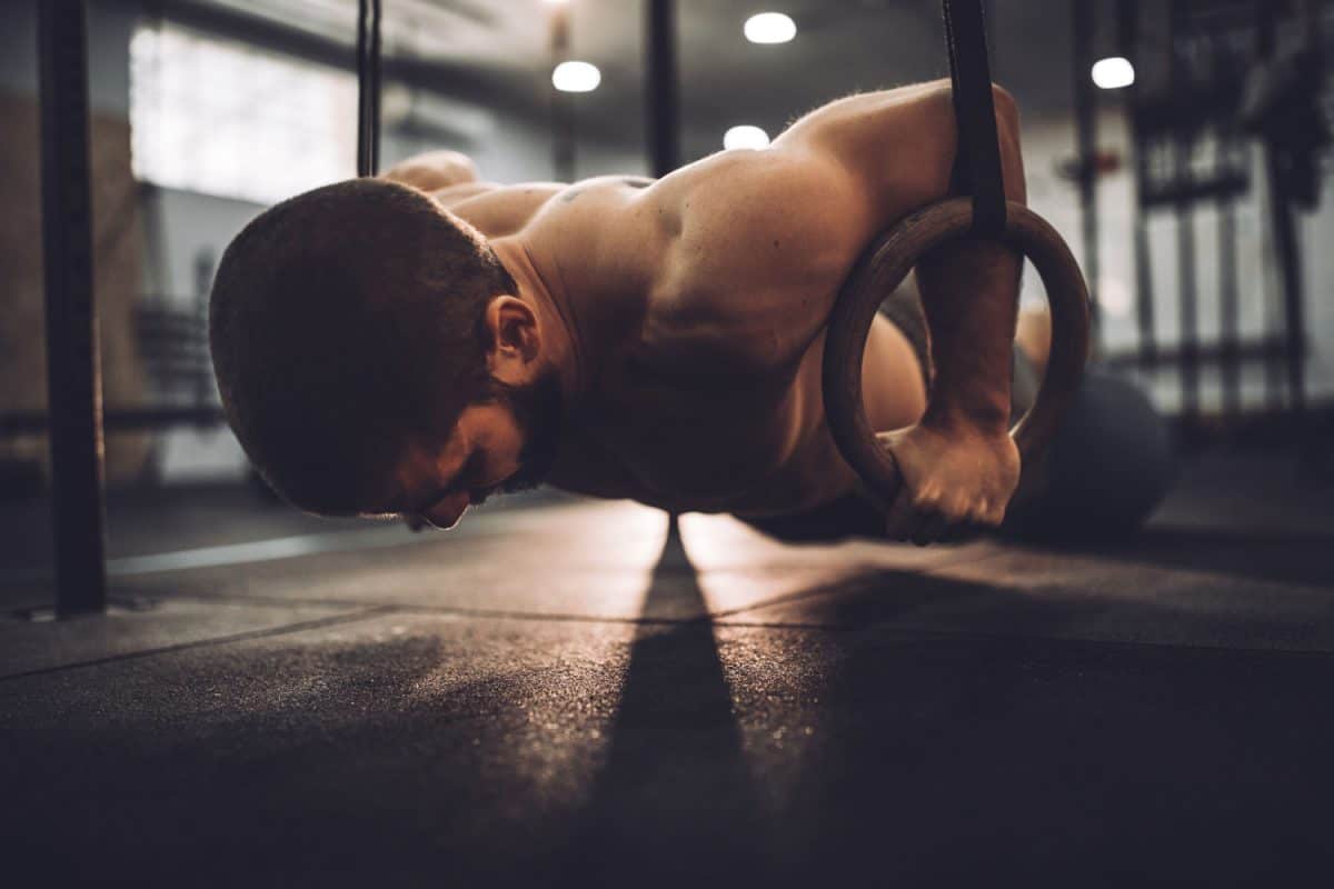 Young muscular man exercising on gymnastic rings