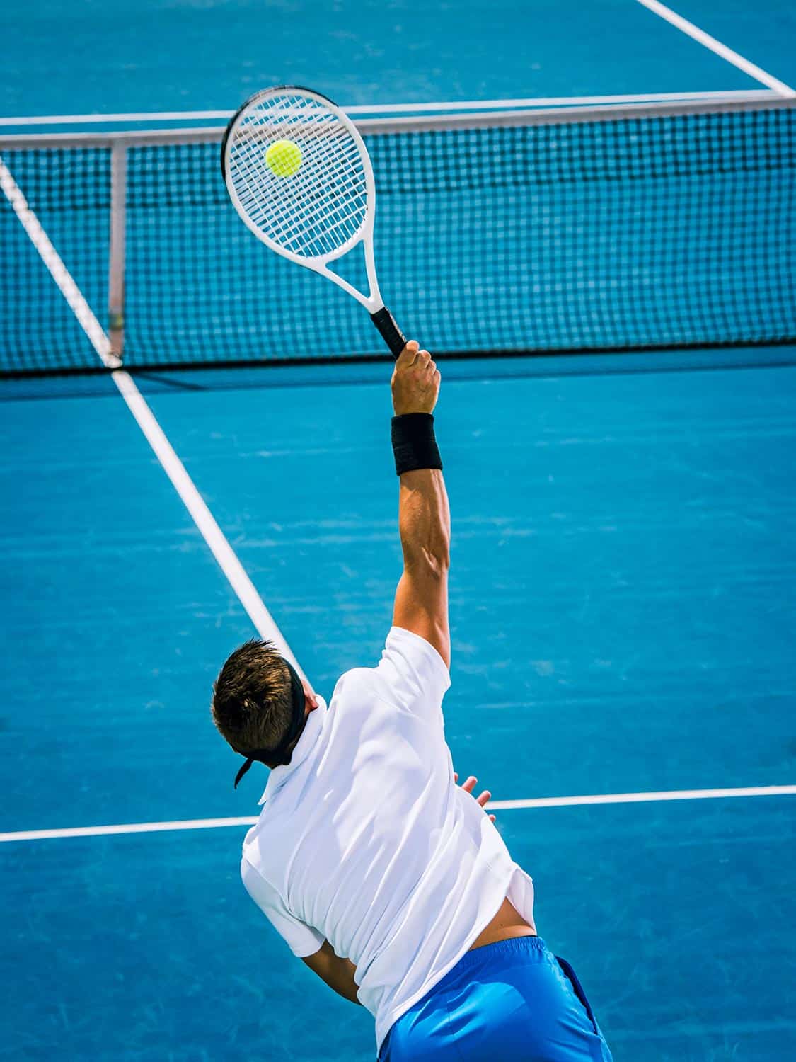 Professional tennis player serving on a blue tennis court