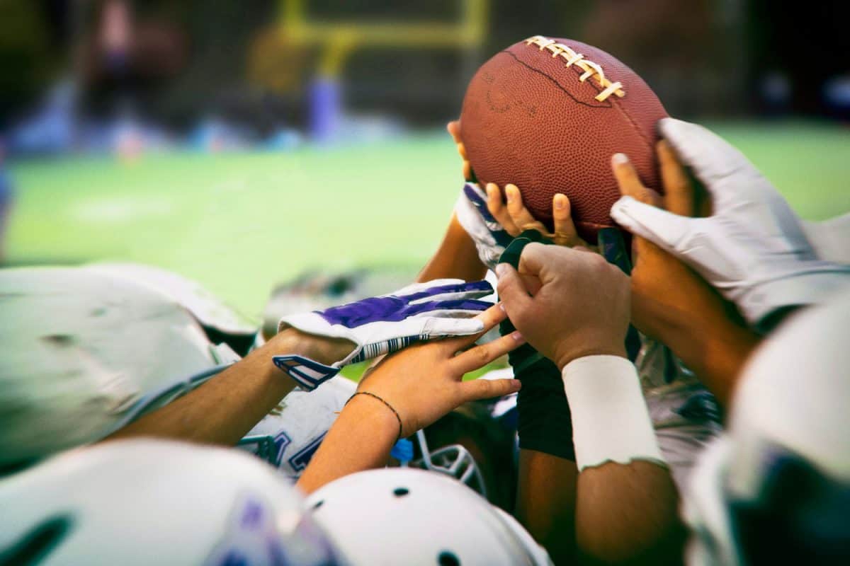 A selective focus photograph of football players getting a hold of the football