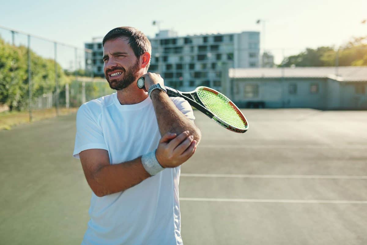 A tennis player holding his elbow to elbow pain