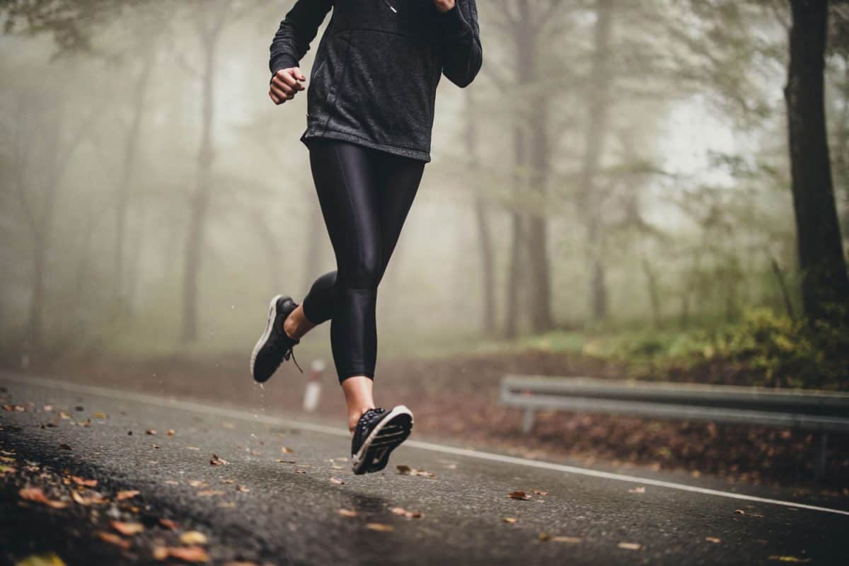 Lady jogger wearing black running shoes, leggings and sweat shirt