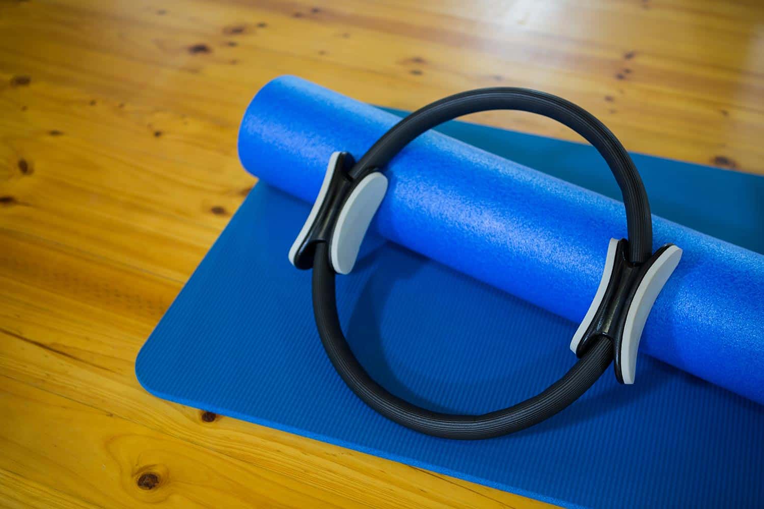 Pilates ring and exercise mat kept on wooden floor in fitness center