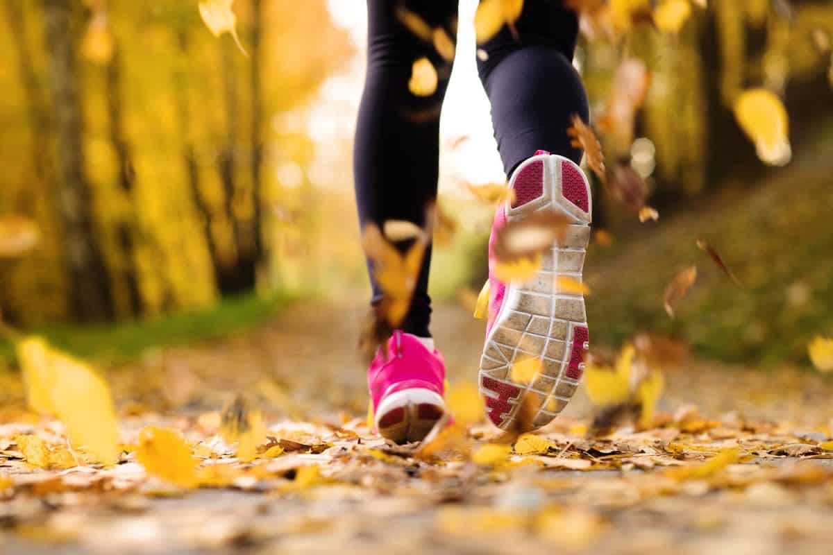 Woman doing a cardio exercise running through leaves