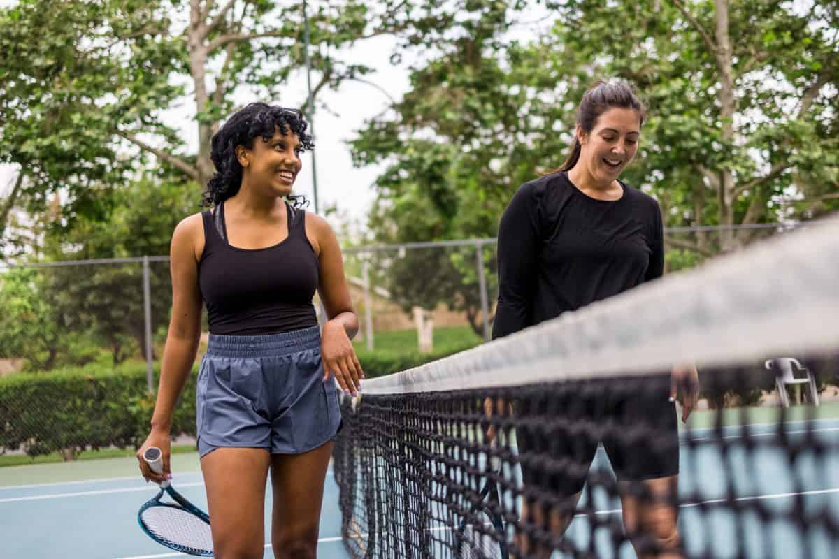 A young black woman and her friend playing tennis