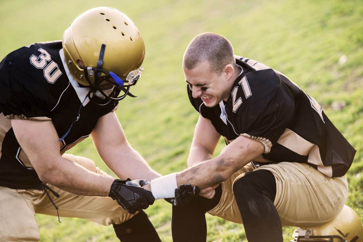 A football player helping his teammate with a dislocated arm