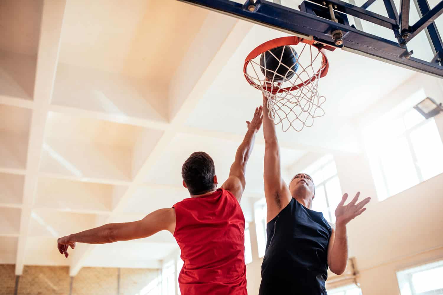 Photo of two basketball players dunking basketball in hoop.