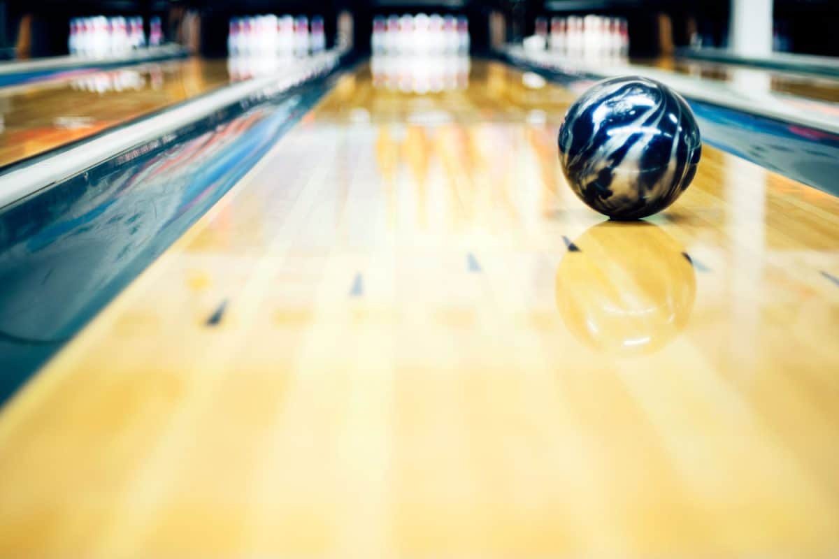 A black resin designed bowling ball rolling along the alley