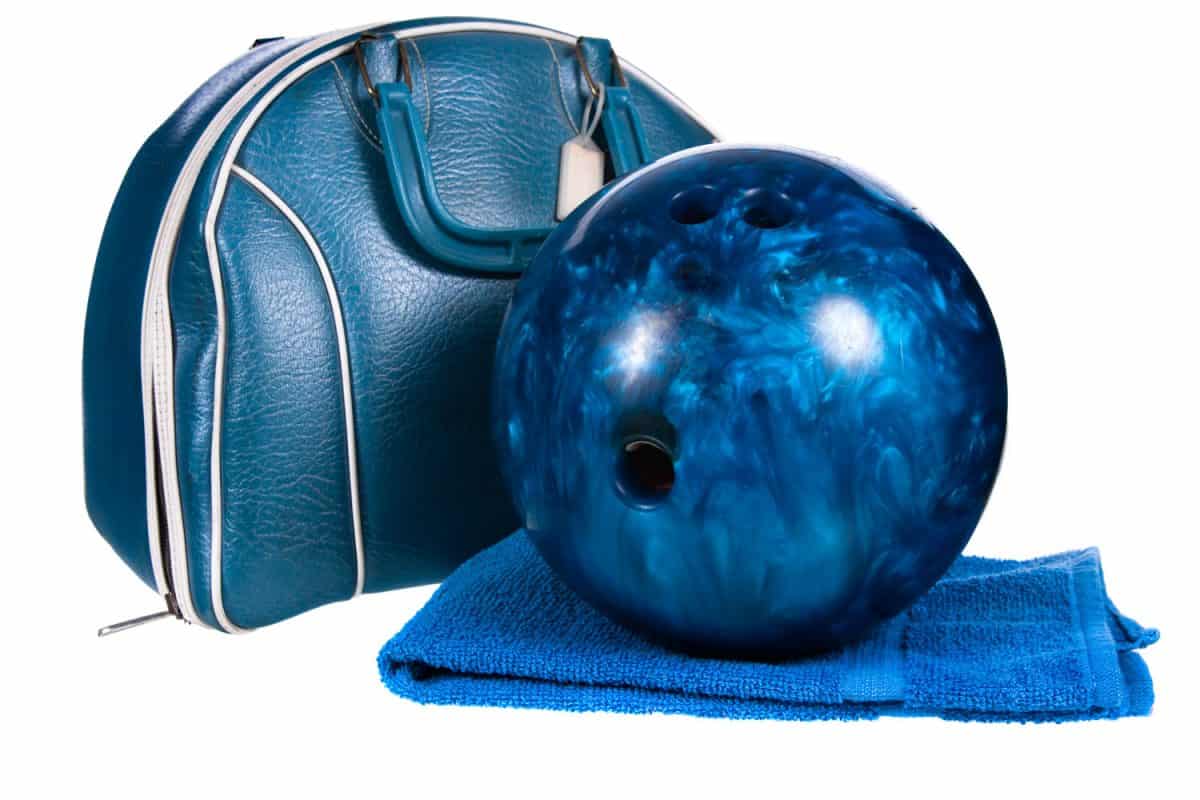 A blue bowling ball placed on top of a towel and a bag on the side