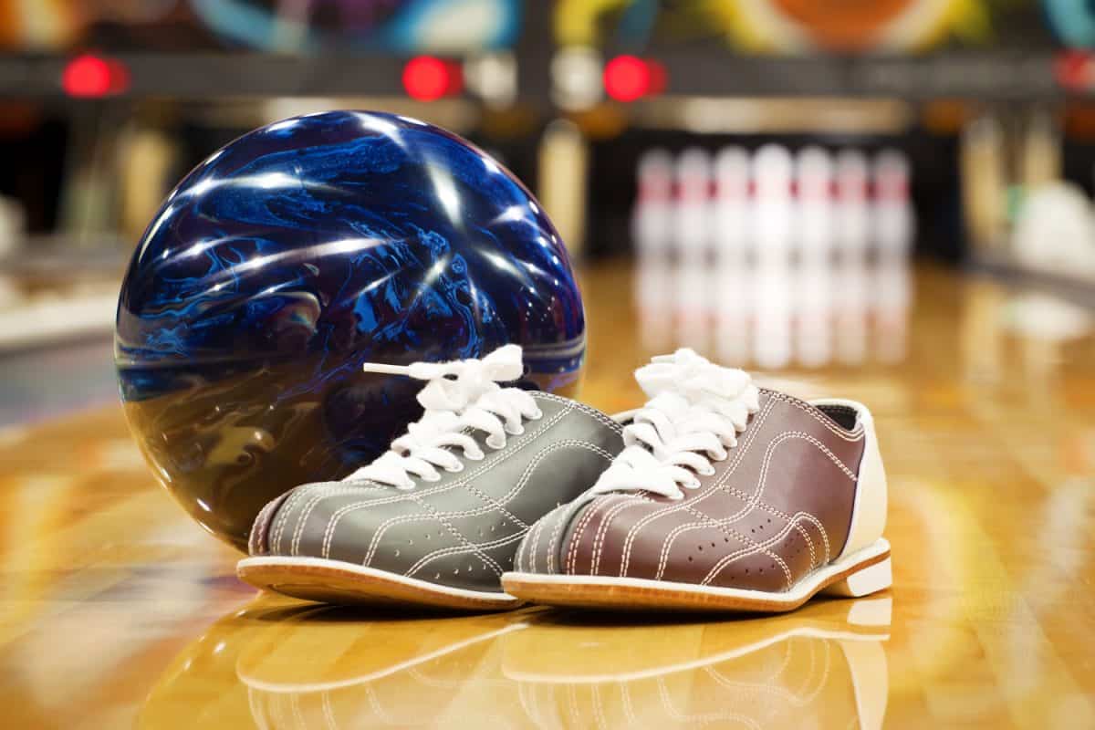 A bowling ball and bowling shoes on the bowling lane