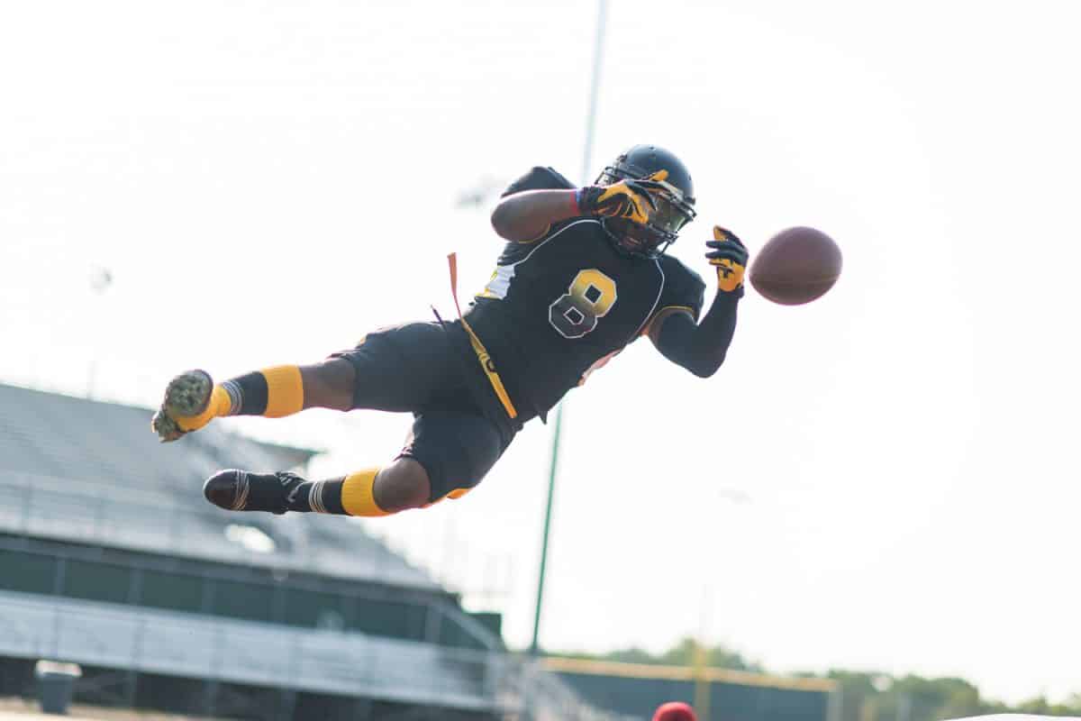 A football player jumping high up and trying to catch the ball