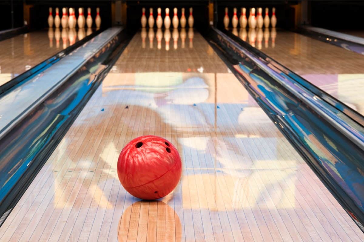 A red colored bowling ball headed for the bowling pins