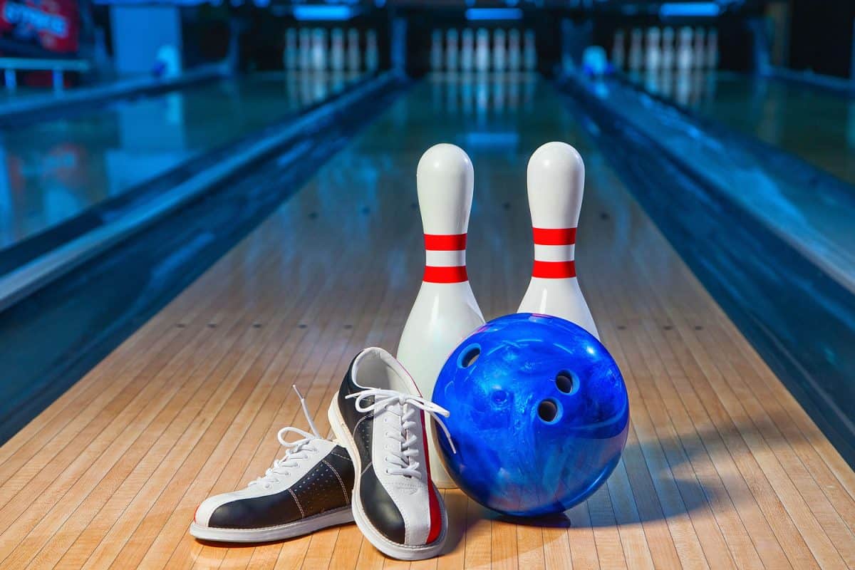 Bowling pins, blue bowling ball and bowling shoes on the alley way