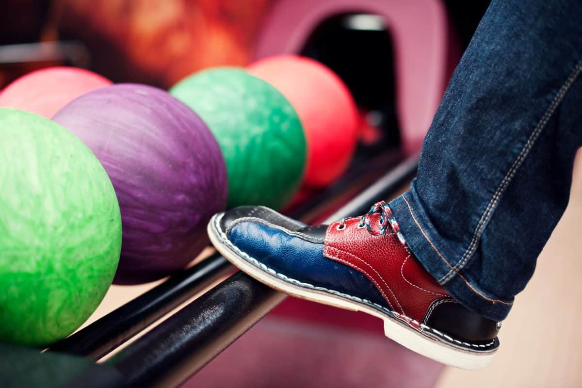 Man putting his shoes near the bowling balls