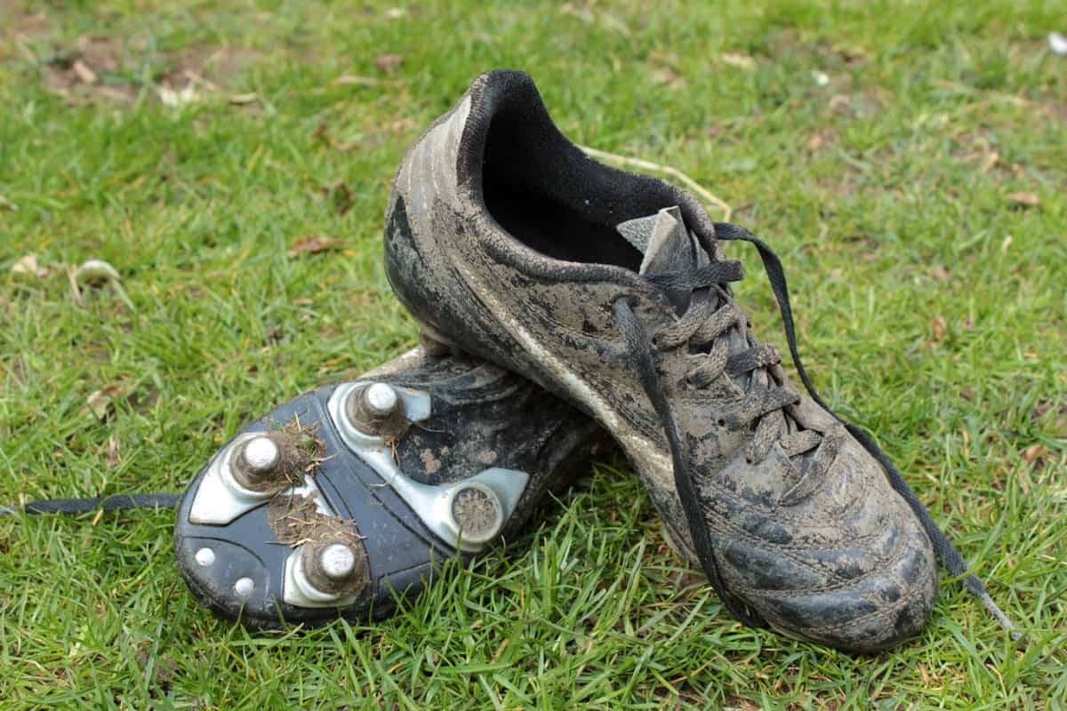 Pair of muddy football boots lying on the grass