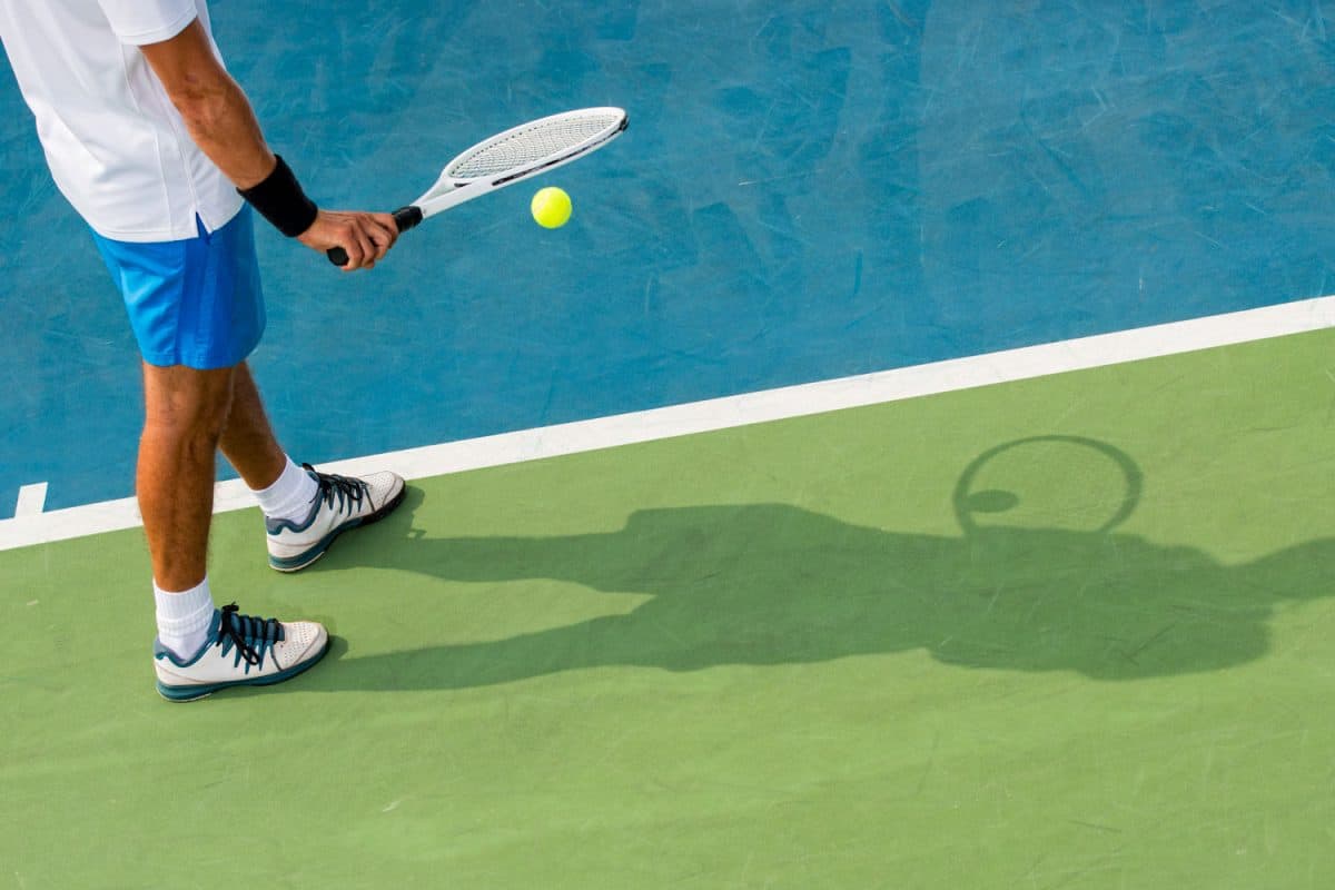 Shadow of a tennis player getting ready to serve the ball
