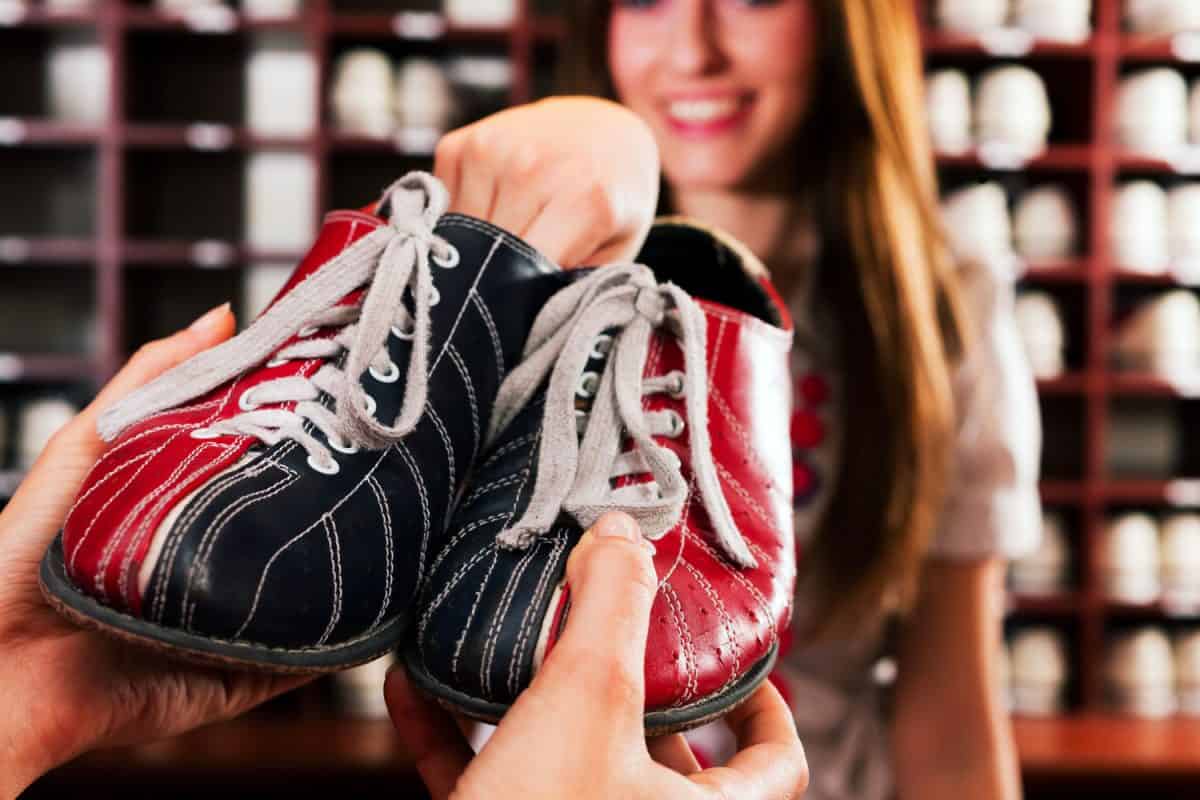 Woman giving bowling shoes to the customer