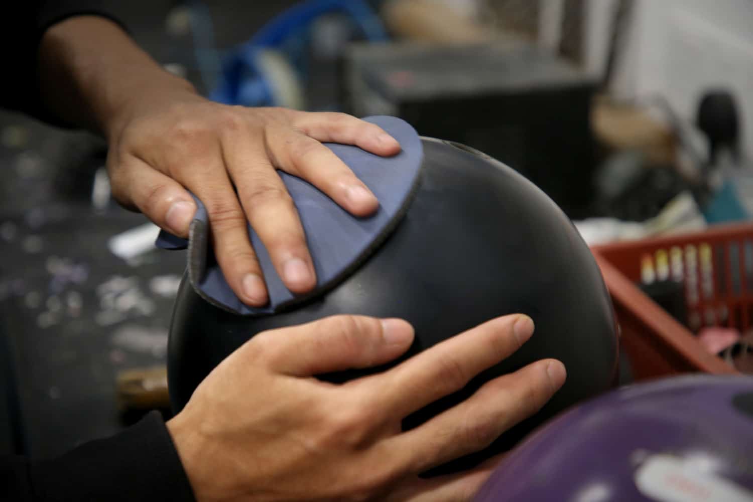 A pair of hands holding a bowling ball and polishing pad for finishing touch.