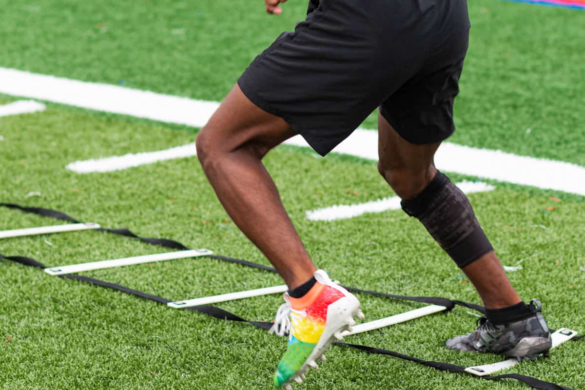 running ladder drills with colorful cleats on a turf field
