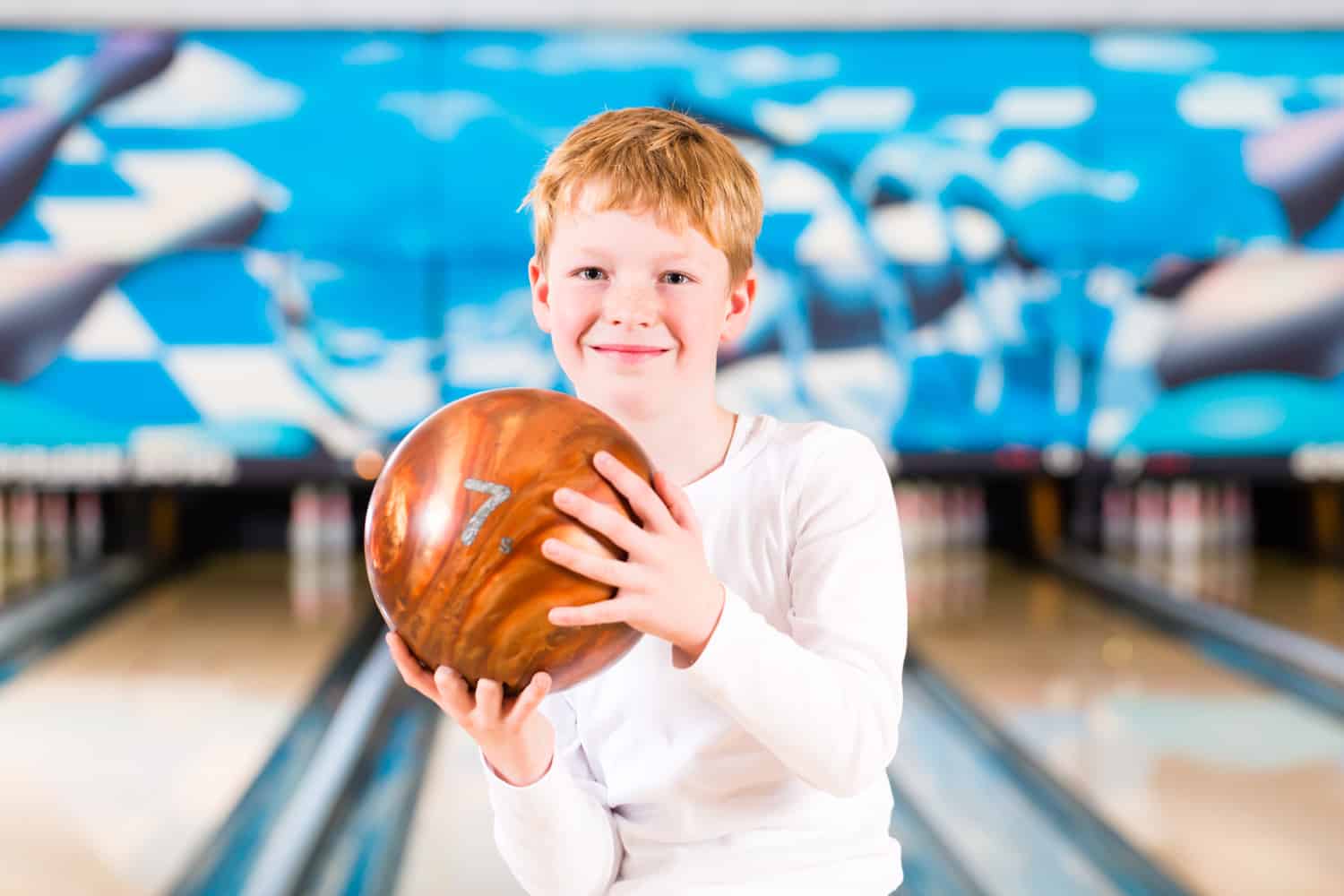 Child bowling with ball in alley