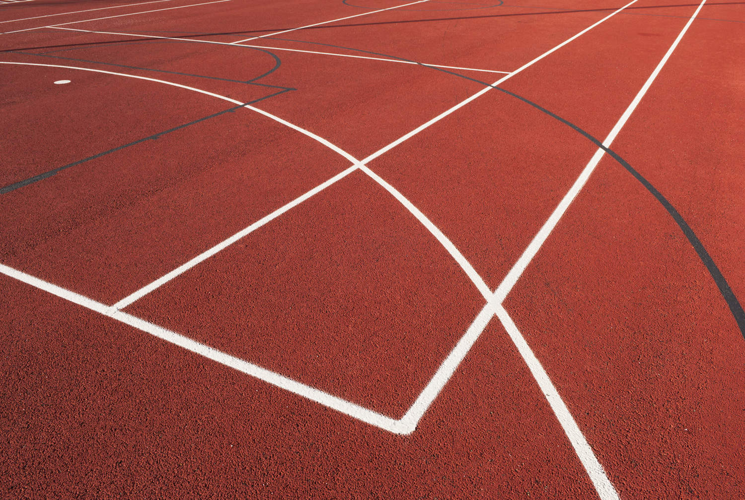 Close up of painted lines on an outdoor sports surface.