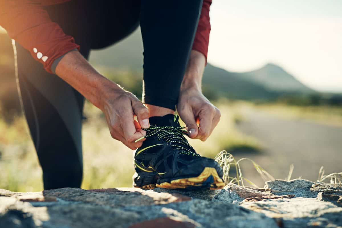 Hiker tying his shoes whilst jogging uphill