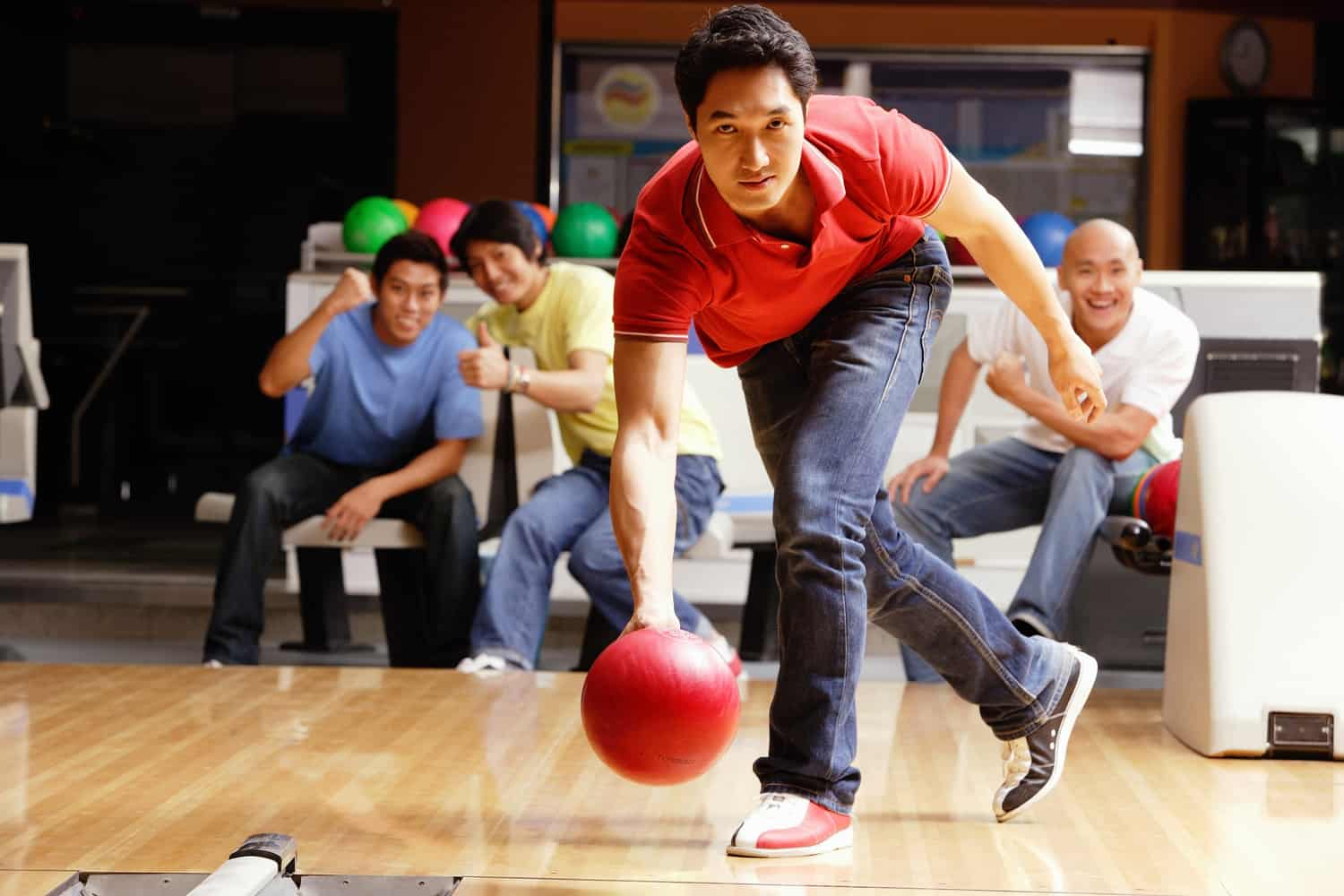 Man bowling, friends cheering in the background