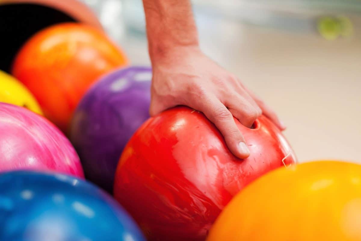 Man grabbing a red bowling ball
