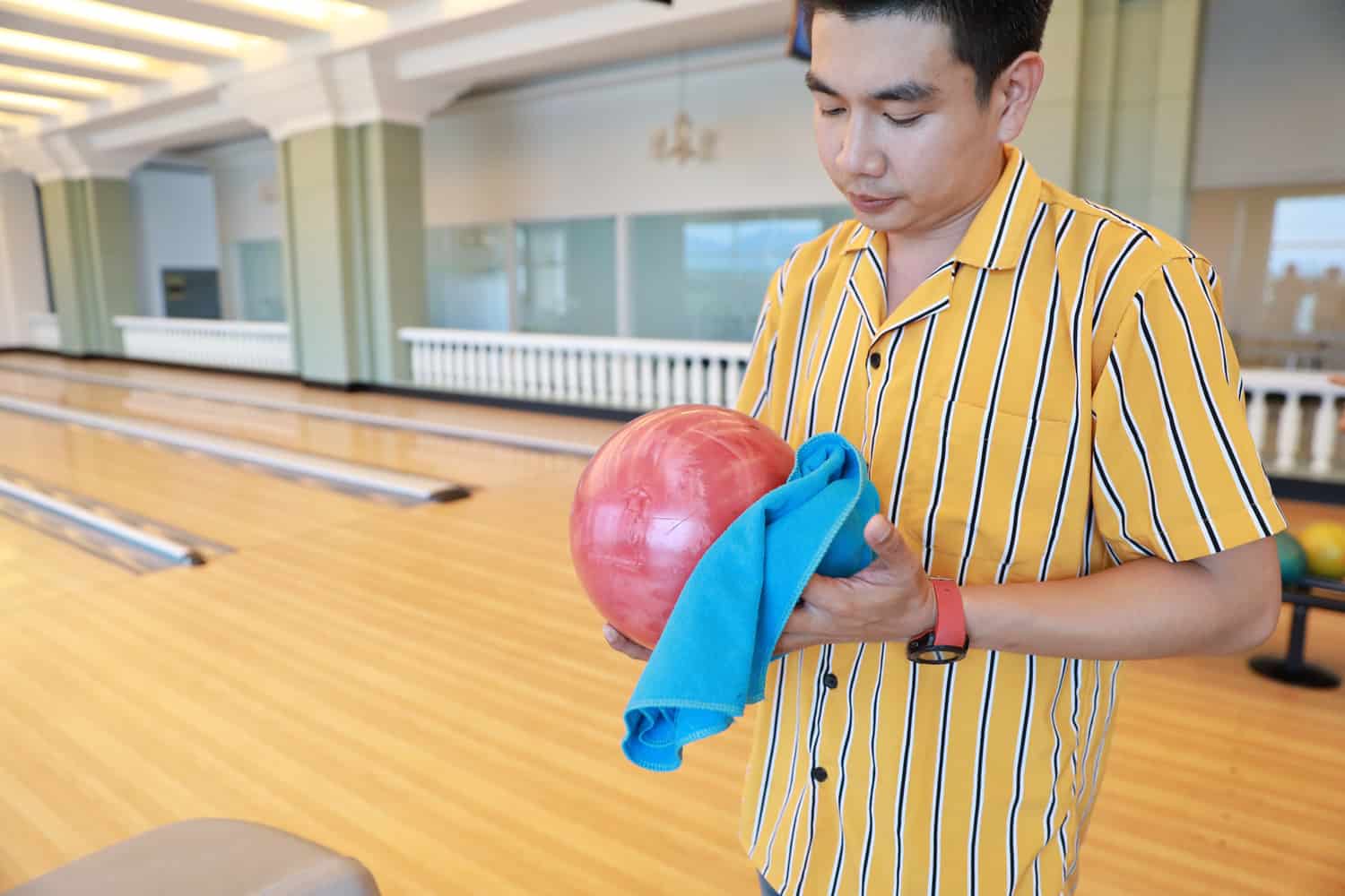 man holding and cleaning bowling ball in sport club
